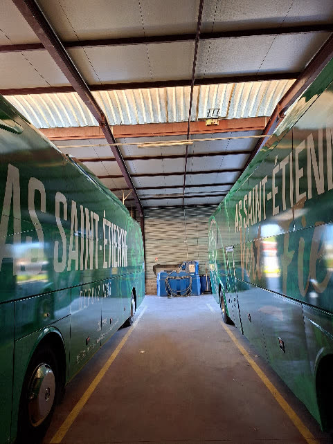 Deux autocars aux couleurs de l'AS Saint-Étienne alignés au dépôt avant le départ