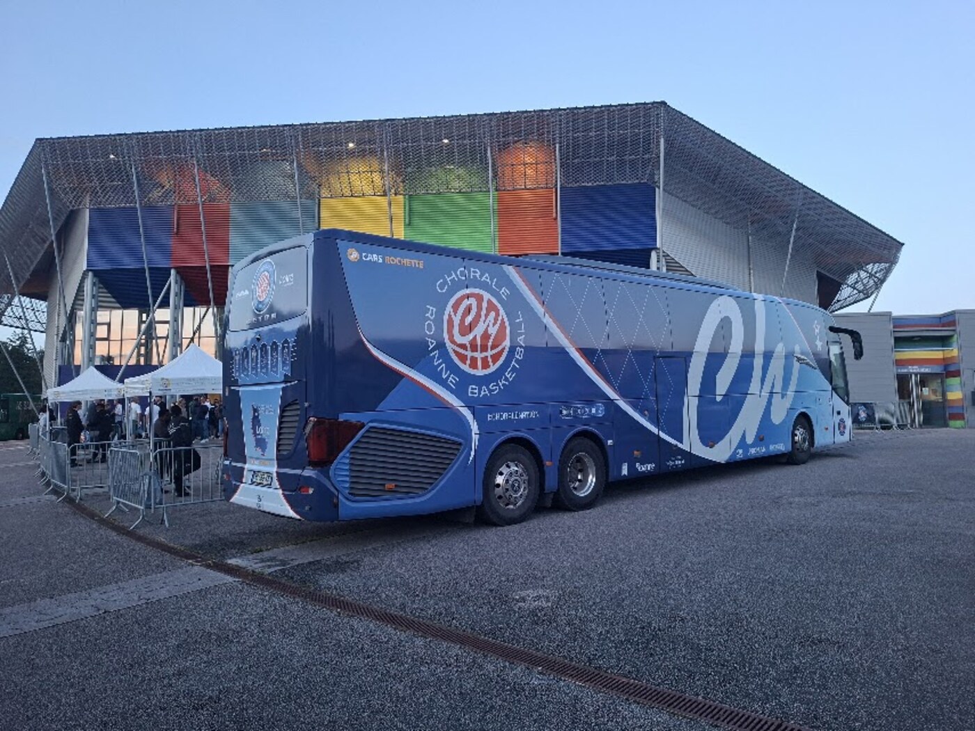 Autocar de la Chorale de Roanne Basket devant la salle, à la tombée du jour
